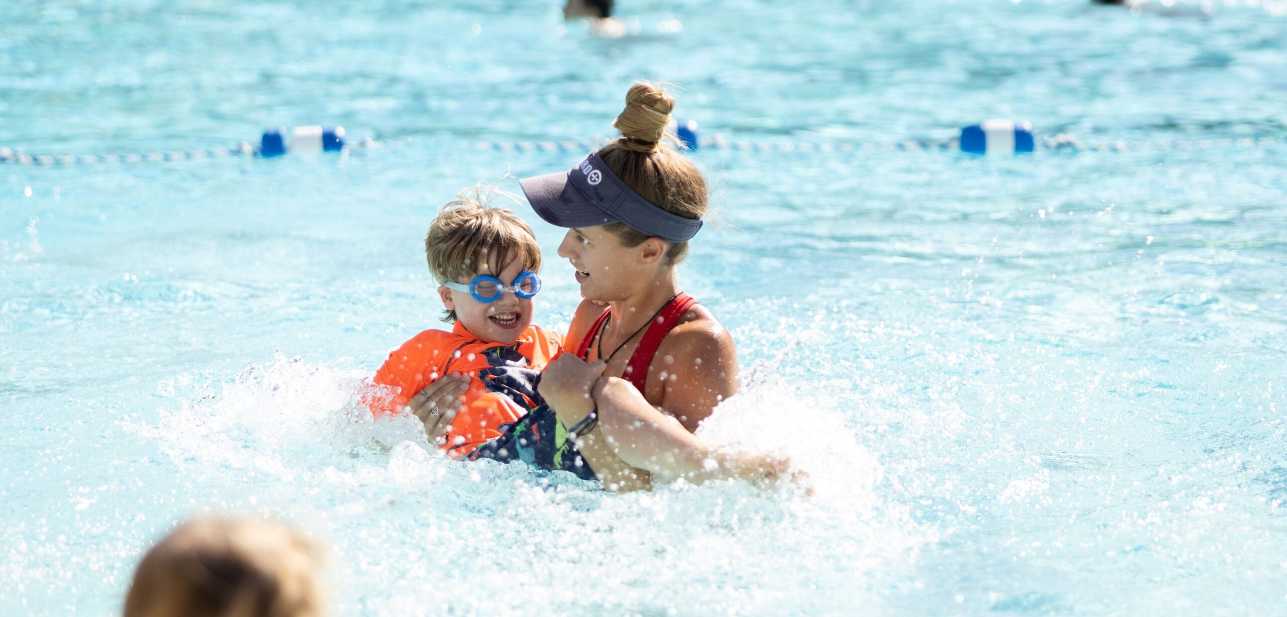 kid at swim lessons with instructor helping him swim