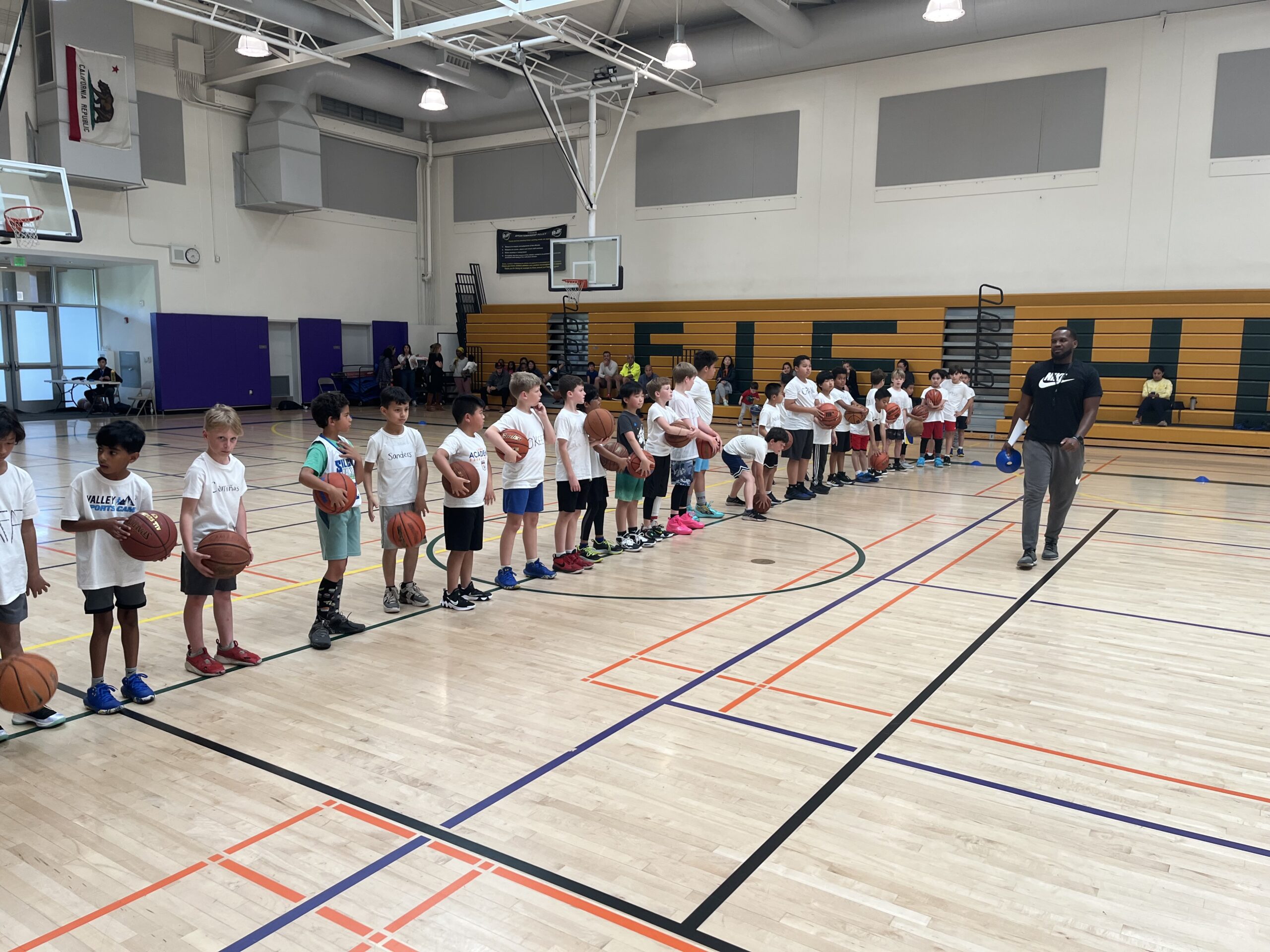 Kids lined up with basketballs with coach Will