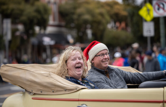 Holiday Parade couple in back of old car