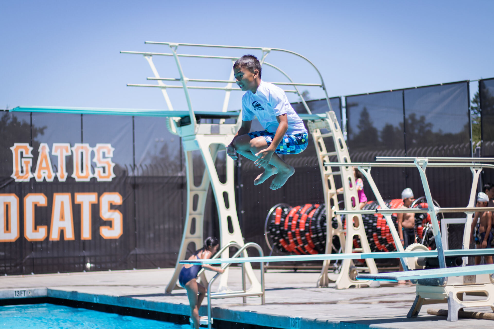 Kid doing cannonball off diving board ino pool
